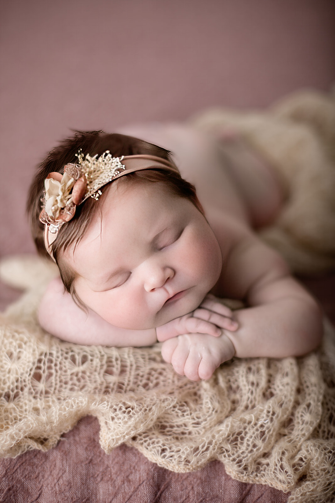 A newborn baby girl sleeps on a blanket with a floral headband thanks to Houston Postpartum Doulas