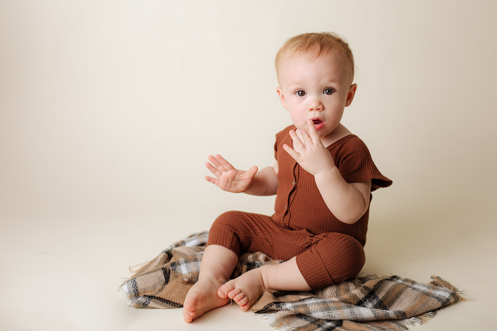 A young toddler in a red onesie sits on the floor of a studio before some mommy and me classes in houston